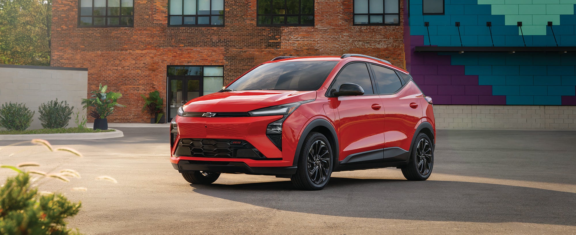 Red 2027 Chevrolet Bolt parked outside a building